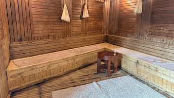 A sauna with wooden benches, a small stool, and towels.