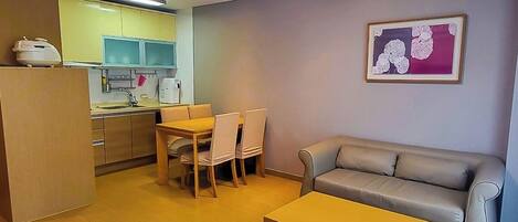 A compact living space with a dining area, a sofa, and a kitchen in the background.