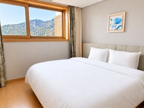 Un dormitorio con una cama grande, vistas a las montañas a través de una ventana y un cuadro en la pared.