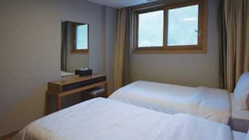 Two single beds with crisp white linens, a nightstand with a lamp, and a mirror complete this serene space.