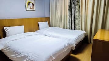 A hotel room with two beds, a wooden headboard, a bedside table, and a framed picture on the wall.