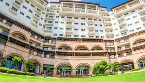 A multi-story hotel with a central courtyard, balconies, and a clear sky. - STX Resort (Mungyeong)
