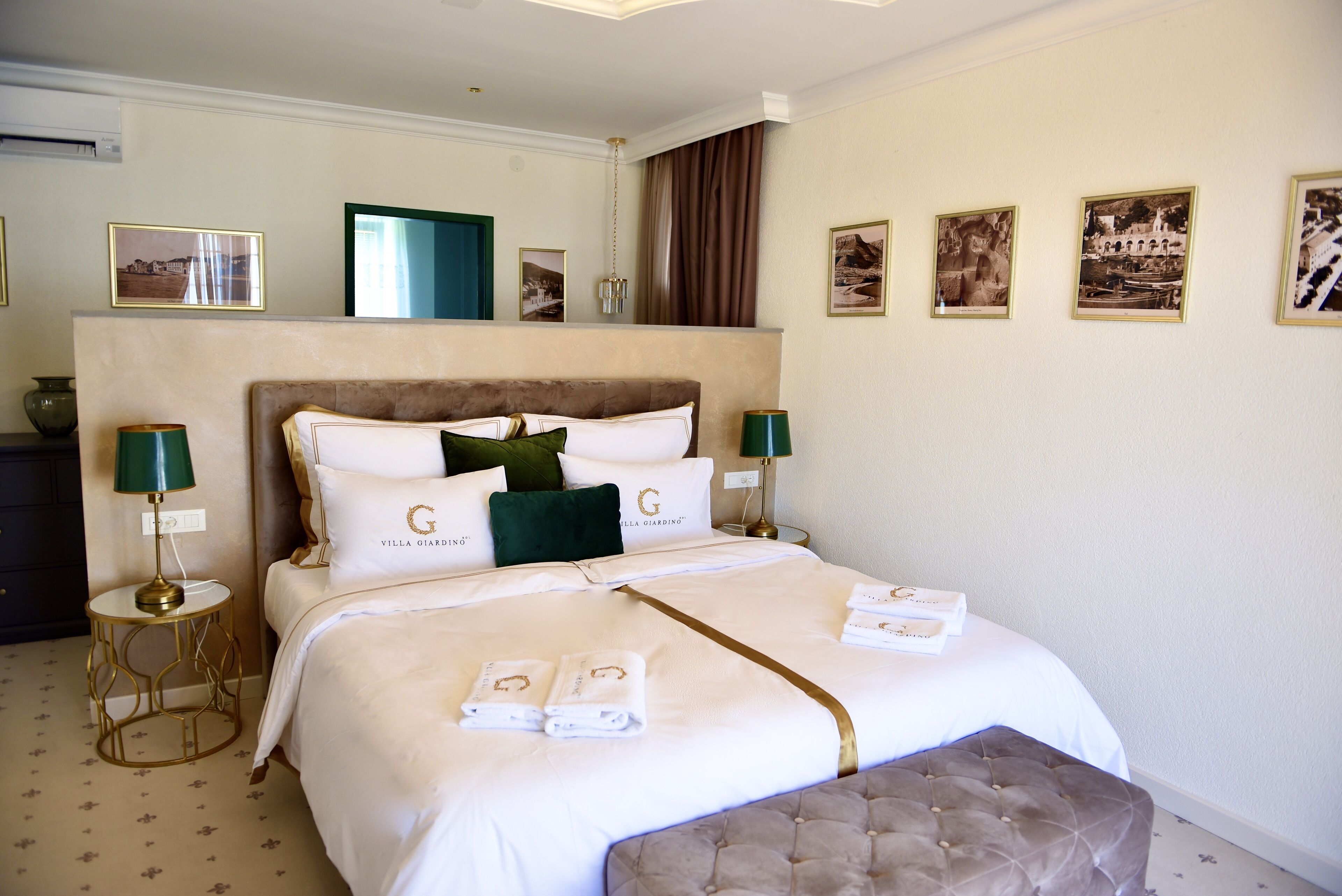 A neatly made bed with a tufted headboard, a bedside table with a lamp, and framed pictures on the wall.