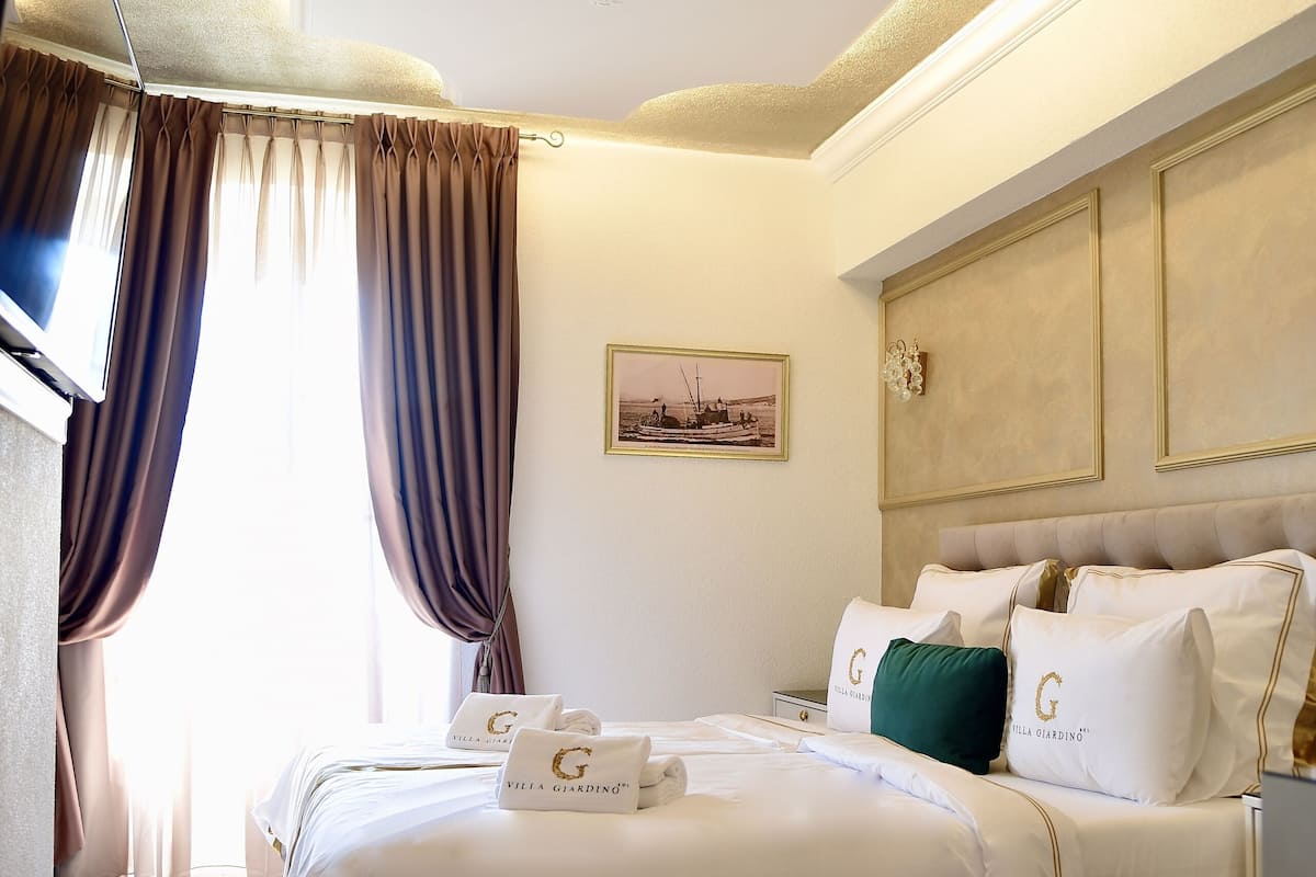 A hotel room with a large bed, a television, and a painting on the wall.