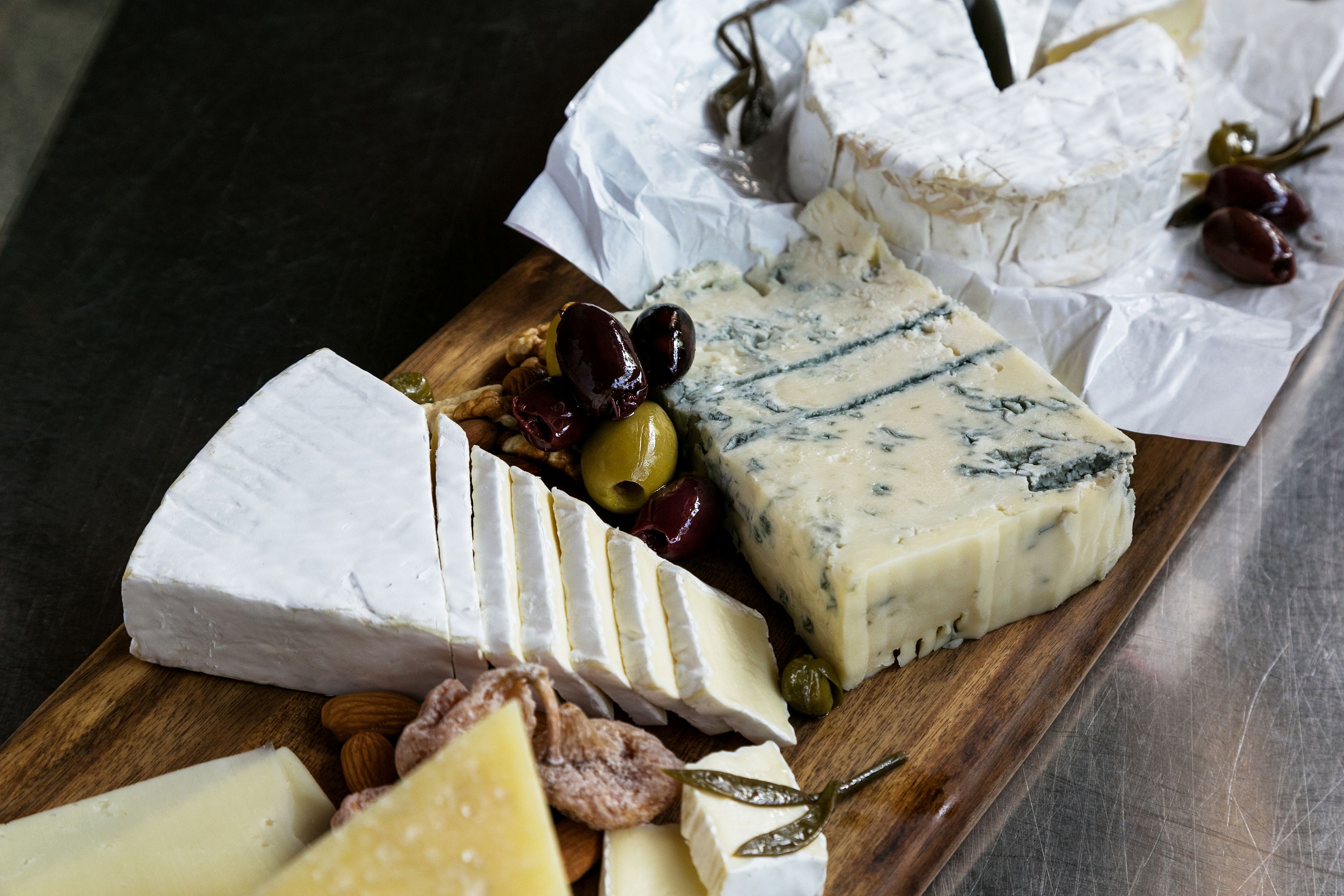 A variety of cheeses and nuts on a wooden board.