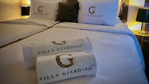 A neatly made bed with white linens and pillows, each featuring the logo "Villa Giardino". - Villa Giardino Heritage Boutique Hotel Bol (Bol)