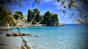 A coastal scene with a clear blue sea, rocky shoreline, and a building with a bell tower. - Villa Giardino Heritage Boutique Hotel Bol (Bol)