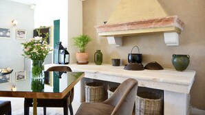 A dining area with a table, chairs, a vase of flowers, a potted plant, and a fireplace mantel with decorative items. - Villa Giardino Heritage Boutique Hotel Bol (Bol)