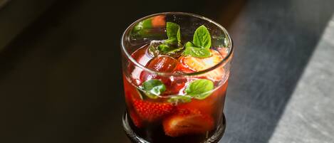 A glass of iced tea with strawberries and mint leaves.