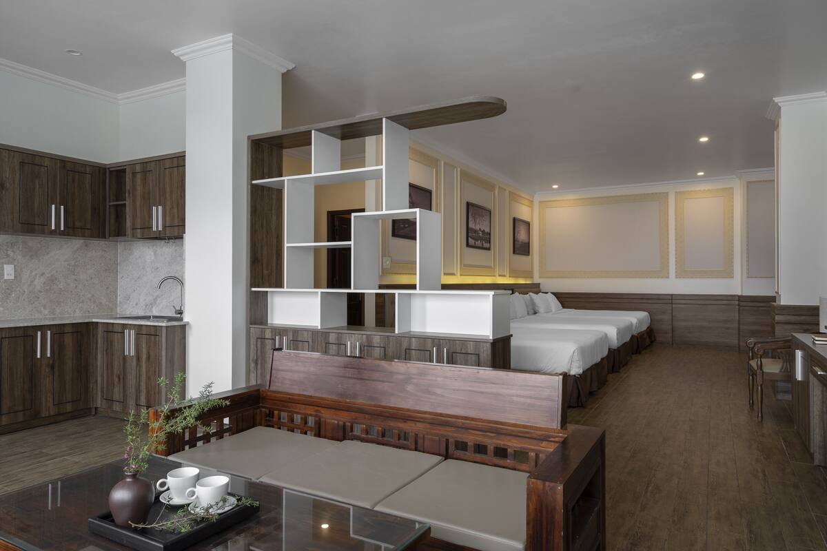 A modern hotel room with a kitchenette, a seating area, and a bed.
