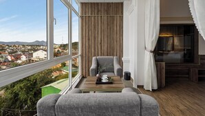 A balcony with a view of a cityscape, a grey armchair, a wooden table with a tray, and a white curtain. - New Life Dalat Hotel (Xuan Huong - Da Lat)