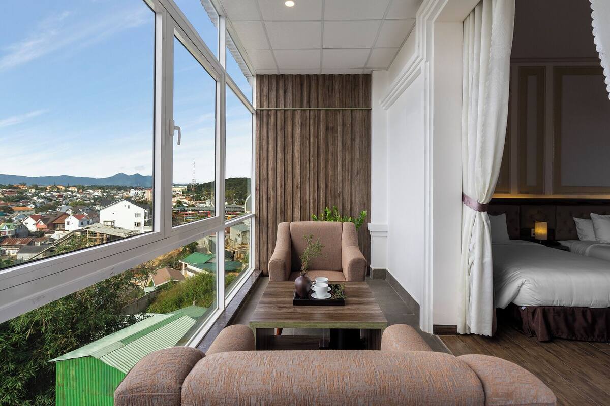 A balcony with a sofa, a table with a vase and cups, and a bed with white bedding.