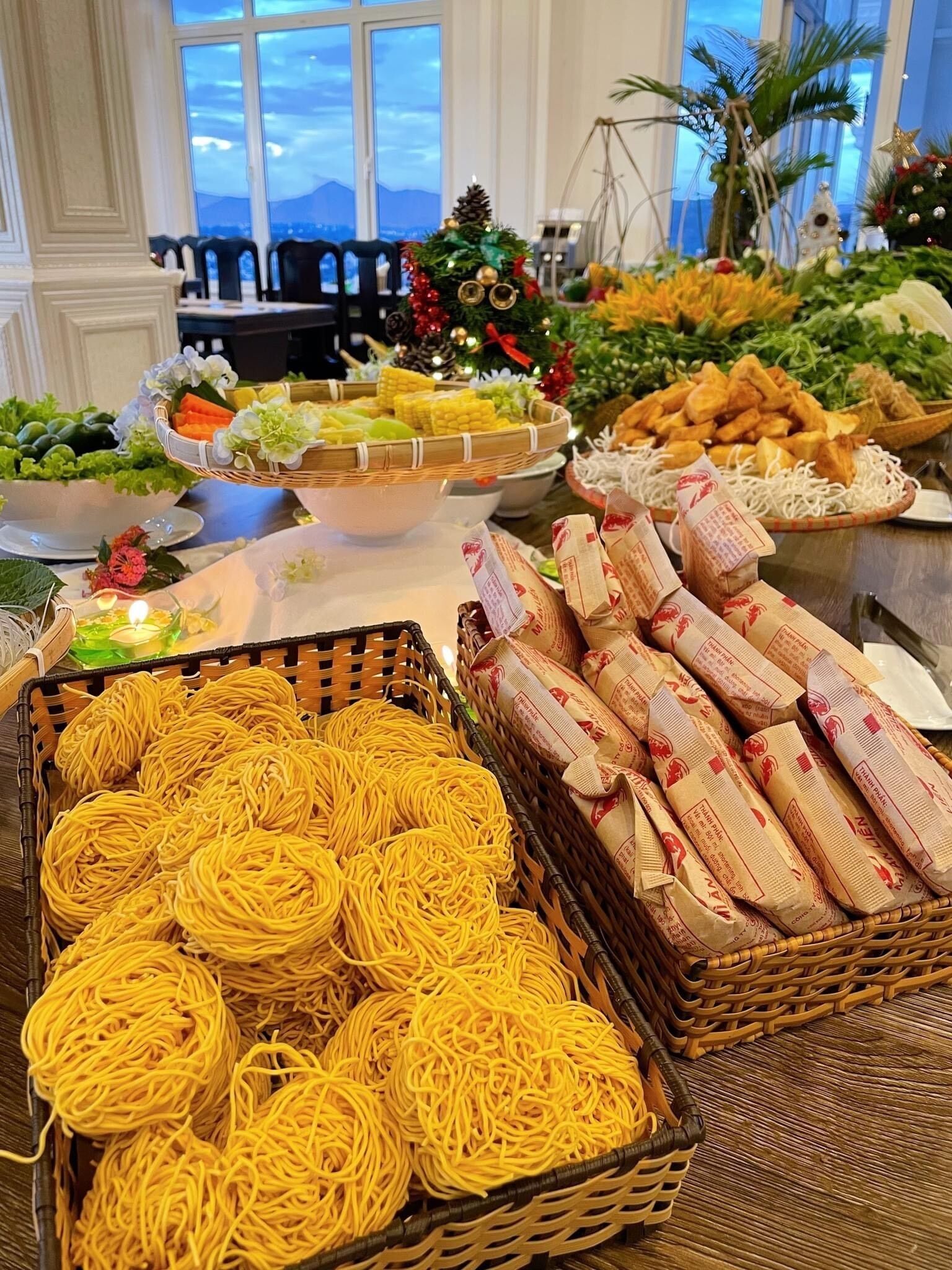 A buffet table with various food items including noodles, vegetables, and fried snacks.