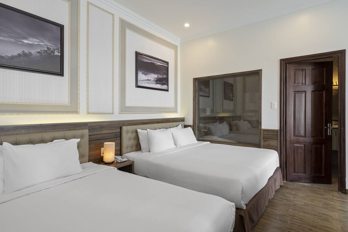 A hotel room with two beds, a large mirror, and framed pictures on the wall.
