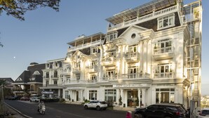 A multi-story hotel with a classic architectural style, featuring balconies and a central entrance. - New Life Dalat Hotel (Xuan Huong - Da Lat)