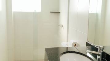 A modern bathroom with a white toilet, a sink with a black countertop, and a large mirror.