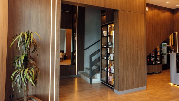Een modern interieur met houten lambrisering, een trap en een displaycase met glazen deuren.