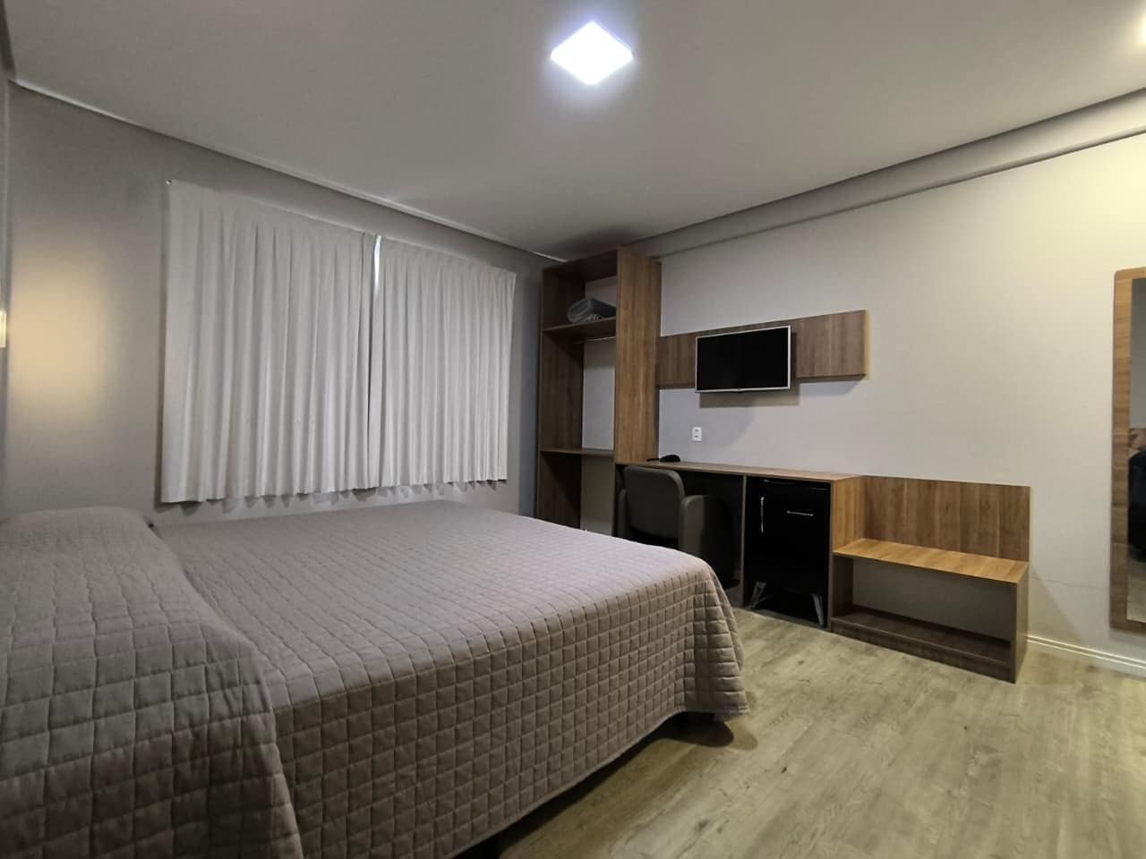 A bedroom with a bed, a desk, a chair, and a television.