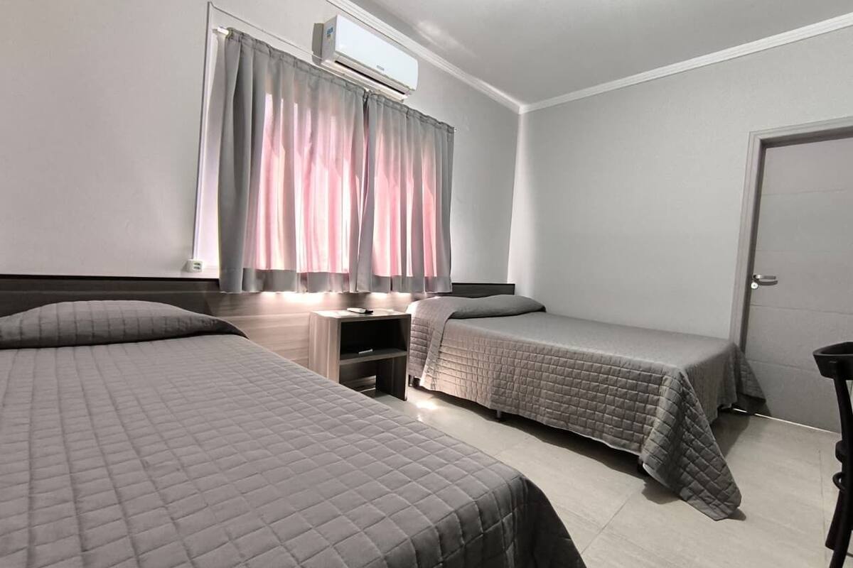 Une chambre avec deux lits, un bureau et un appareil de climatisation.