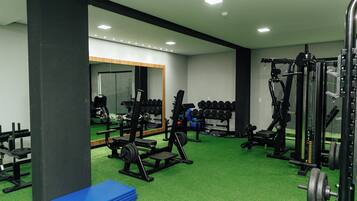 Un gimnasio con equipo de ejercicio diverso, una colchoneta azul y un espejo.