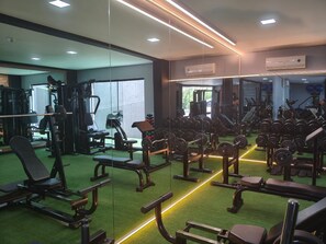 A gym with exercise equipment, mirrors, and green flooring. - Hotel Bergozza (Rio do Sul)