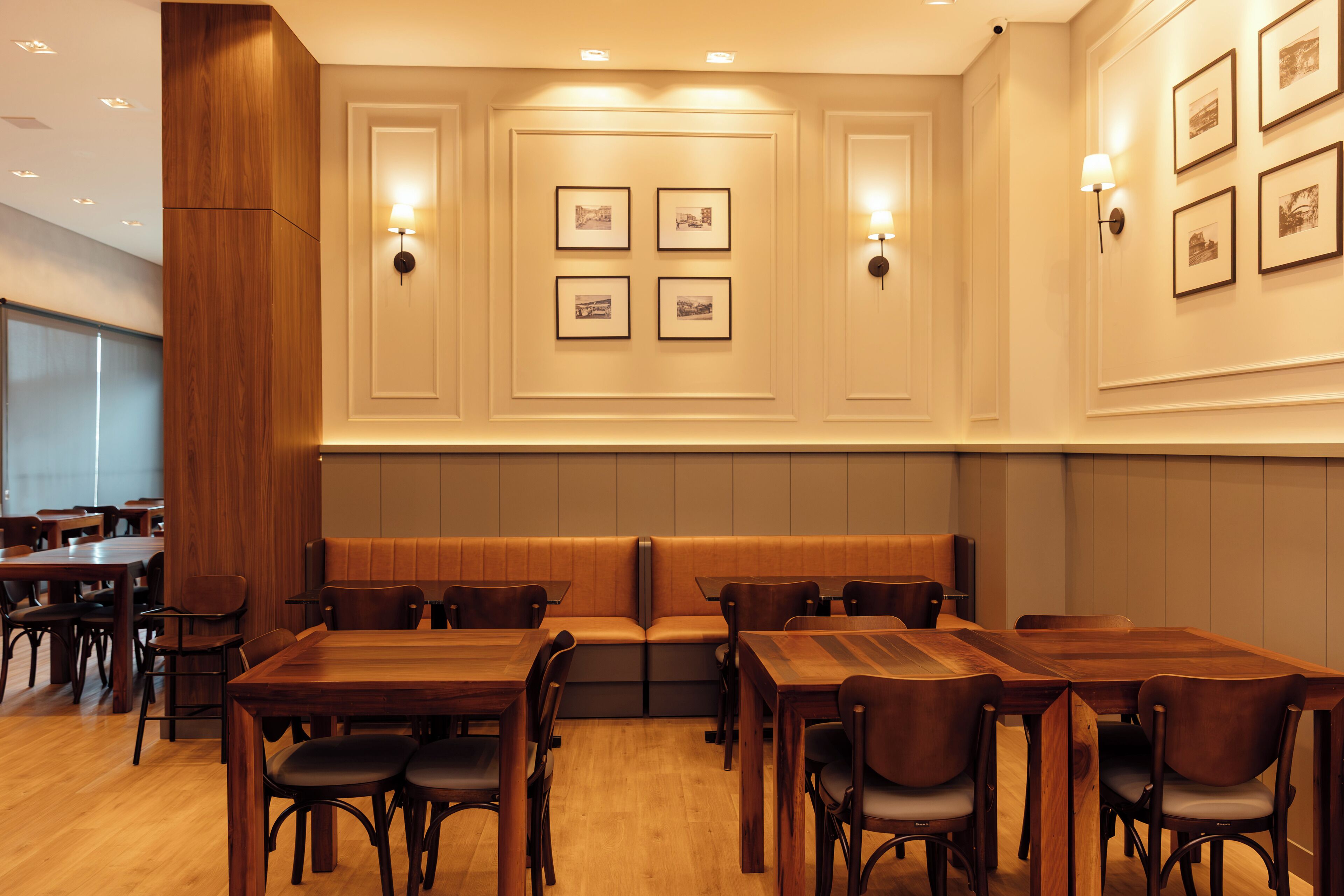 Un restaurante con mesas y cabinas de madera, cuadros en la pared e iluminación empotrada.
