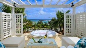 A covered outdoor seating area with a view of the ocean, a hot tub, and a bottle of champagne. - Hotel Shigira Mirage (Miyakojima)
