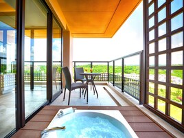 A balcony with a hot tub, chairs, and a table with drinks.