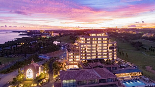 A hotel with multiple floors, a swimming pool, and a view of the sea at sunset. - Hotel Shigira Mirage (Miyakojima)