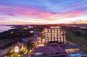 A hotel with multiple floors, a swimming pool, and a view of the sea at sunset. - Hotel Shigira Mirage (Miyakojima)
