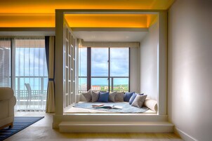 A modern room with a built-in window seat, a white sofa, and a view of the sea.