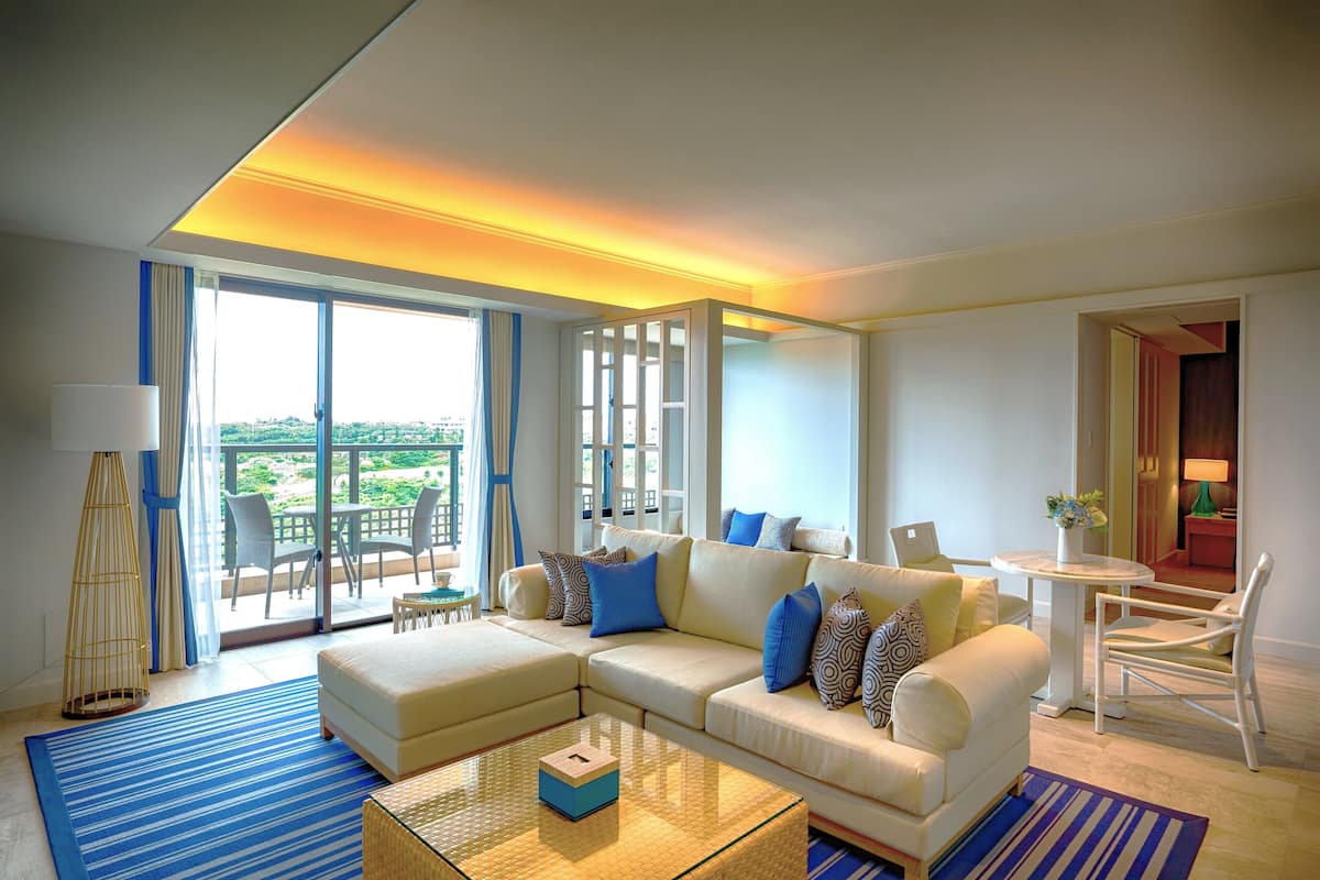A modern living room with a sectional sofa, a glass coffee table, and a view of the outdoors.