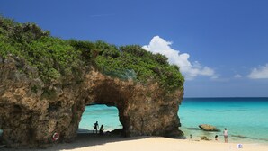 A natural rock arch formation on a beach with clear turquoise water. - Hotel Shigira Mirage (Miyakojima)