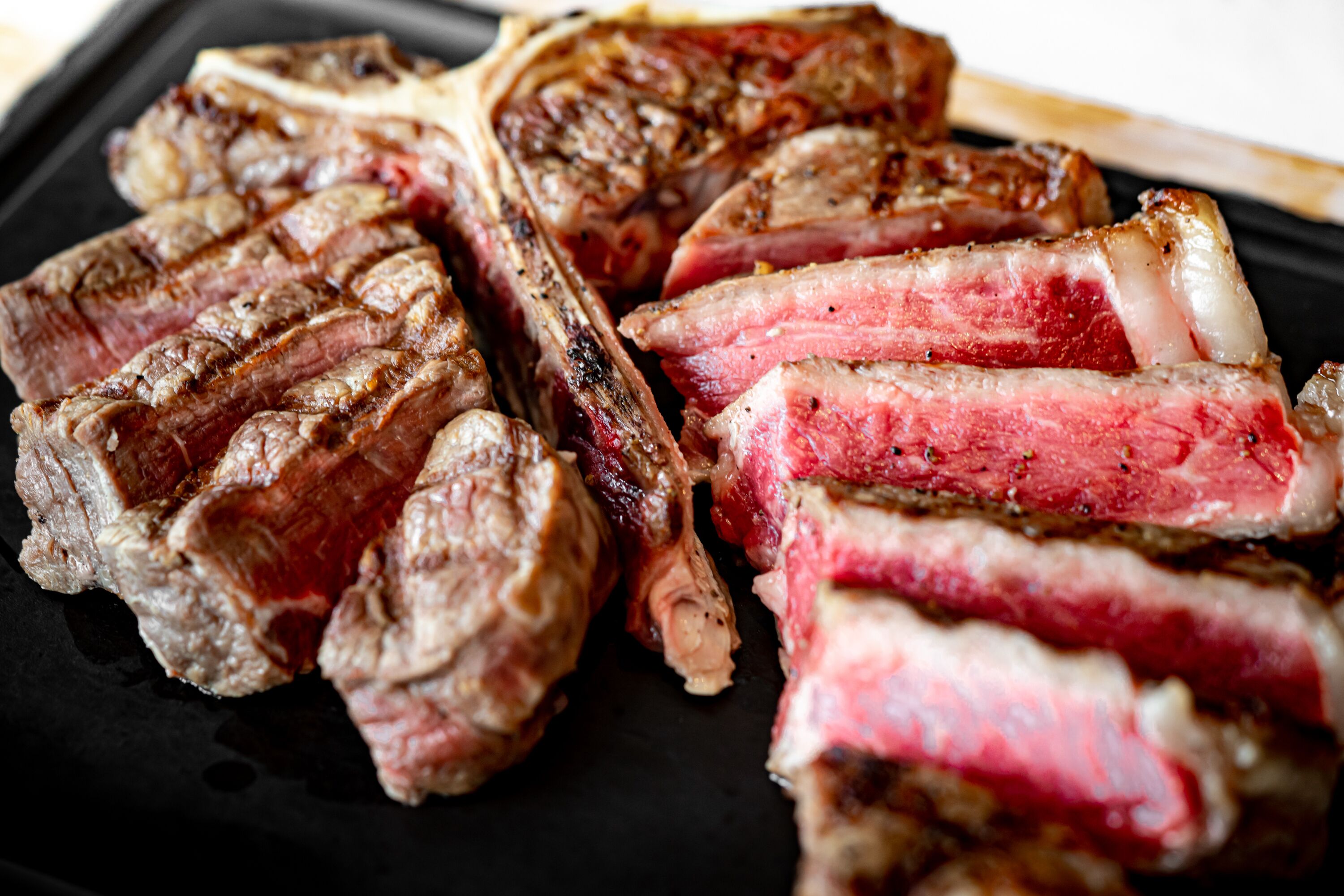 A close-up of a steak with a charred exterior and a pink, juicy interior.