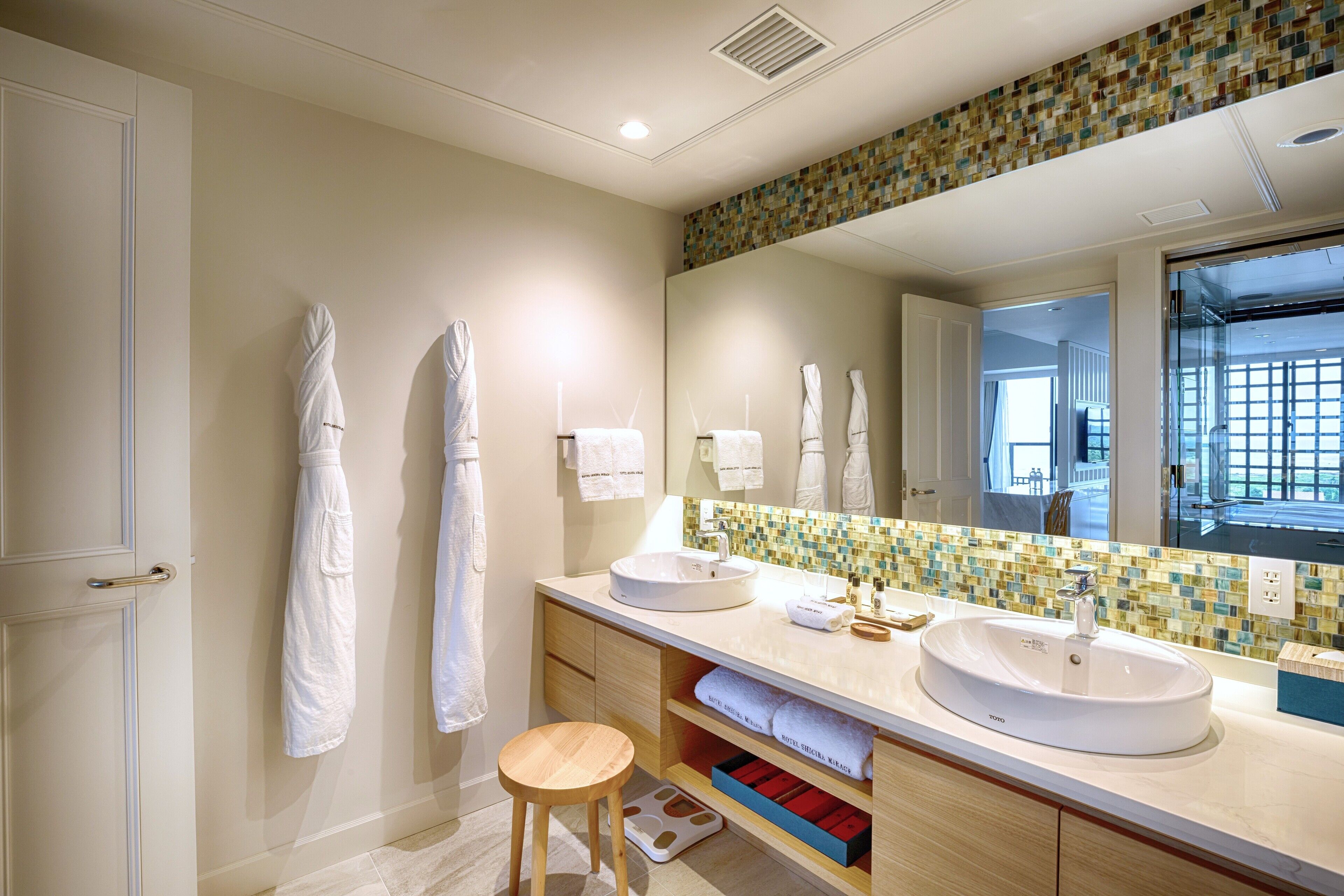 Un baño moderno con dos lavamanos, un espejo grande y un perchero para toallas.
