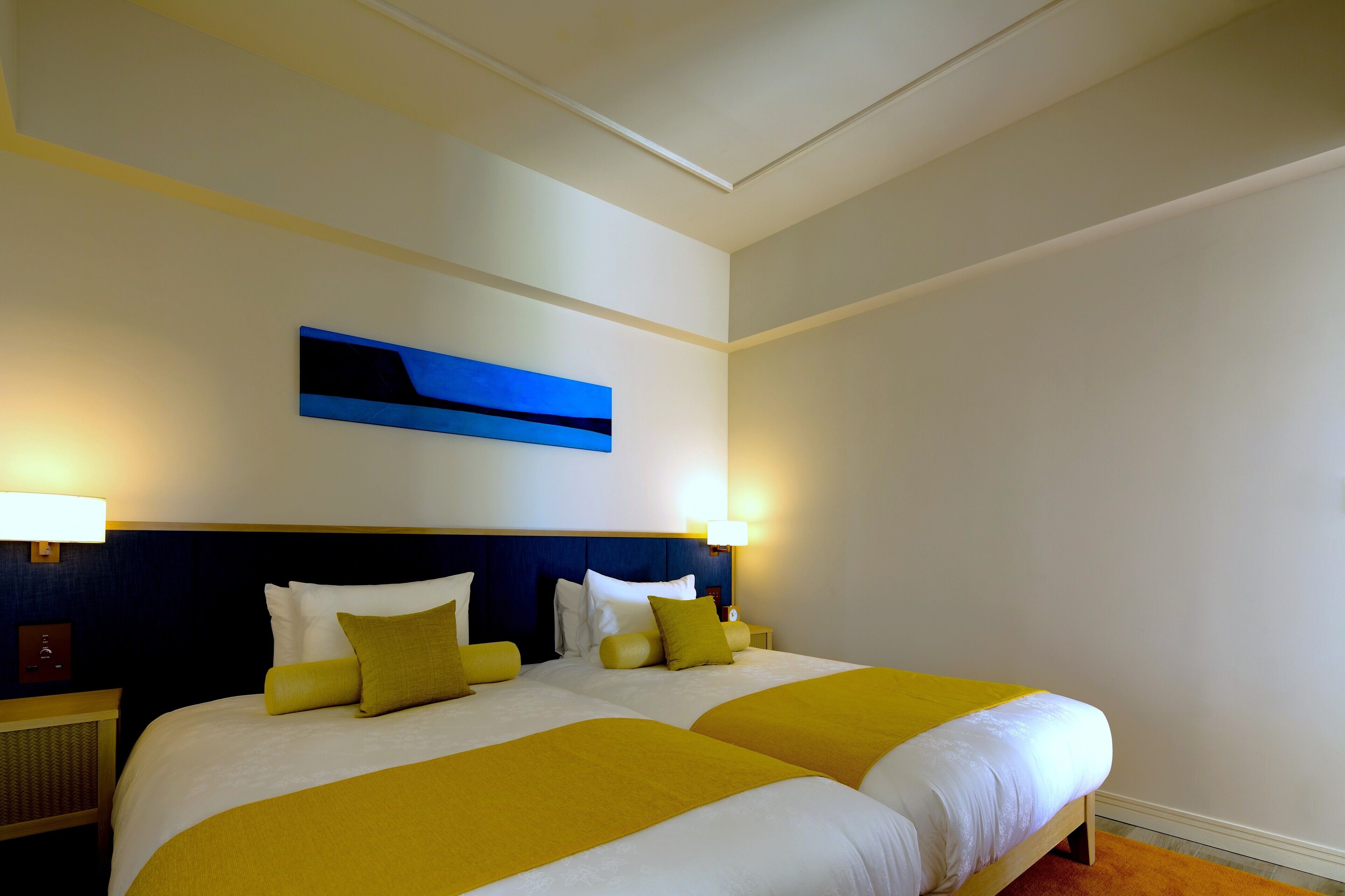 A hotel room with two beds, a blue abstract painting, and two bedside lamps.