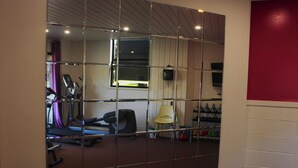 Une salle de sport équipée de matériel d’exercice, d’un tapis de course et d’un téléviseur fixé au mur.