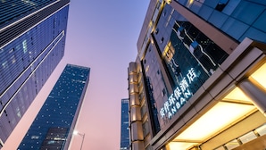 A modern hotel with a prominent sign, tall surrounding buildings, and a clear sky. - Anban Hotel (Shenzhen)