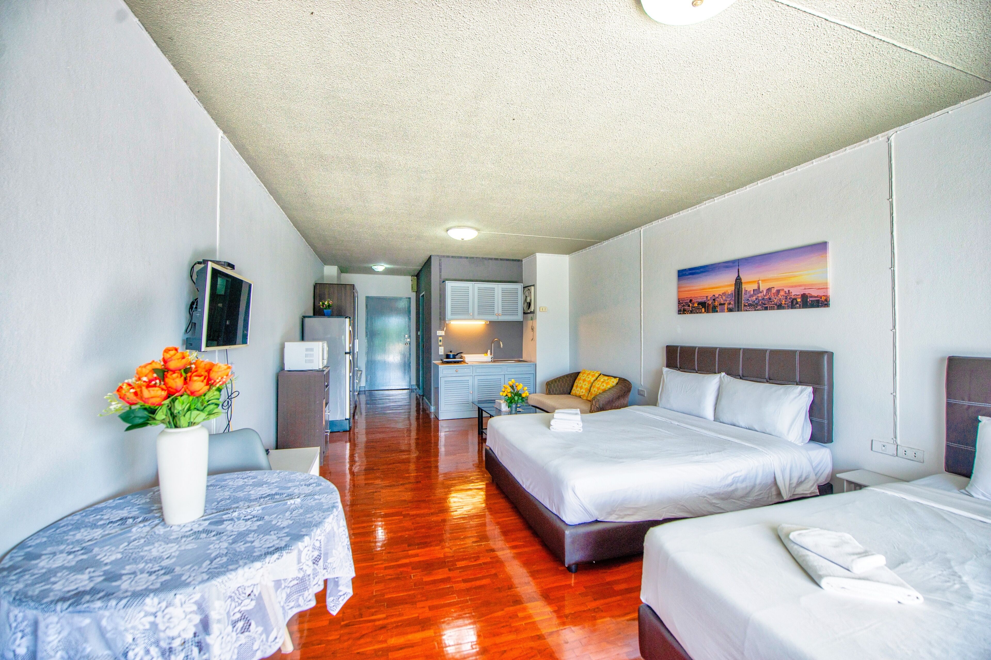 A hotel room with two beds, a dining area, and a kitchenette.