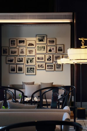 A room with a wall of framed black and white photographs, a sofa, and a table with chairs.
