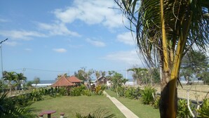 A tropical garden with a pathway leading to a beach. - Emir surfcamp (Pekutatan)
