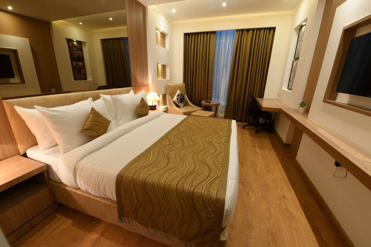 Een hotelkamer met een groot bed, een bureau, een stoel en een televisie.