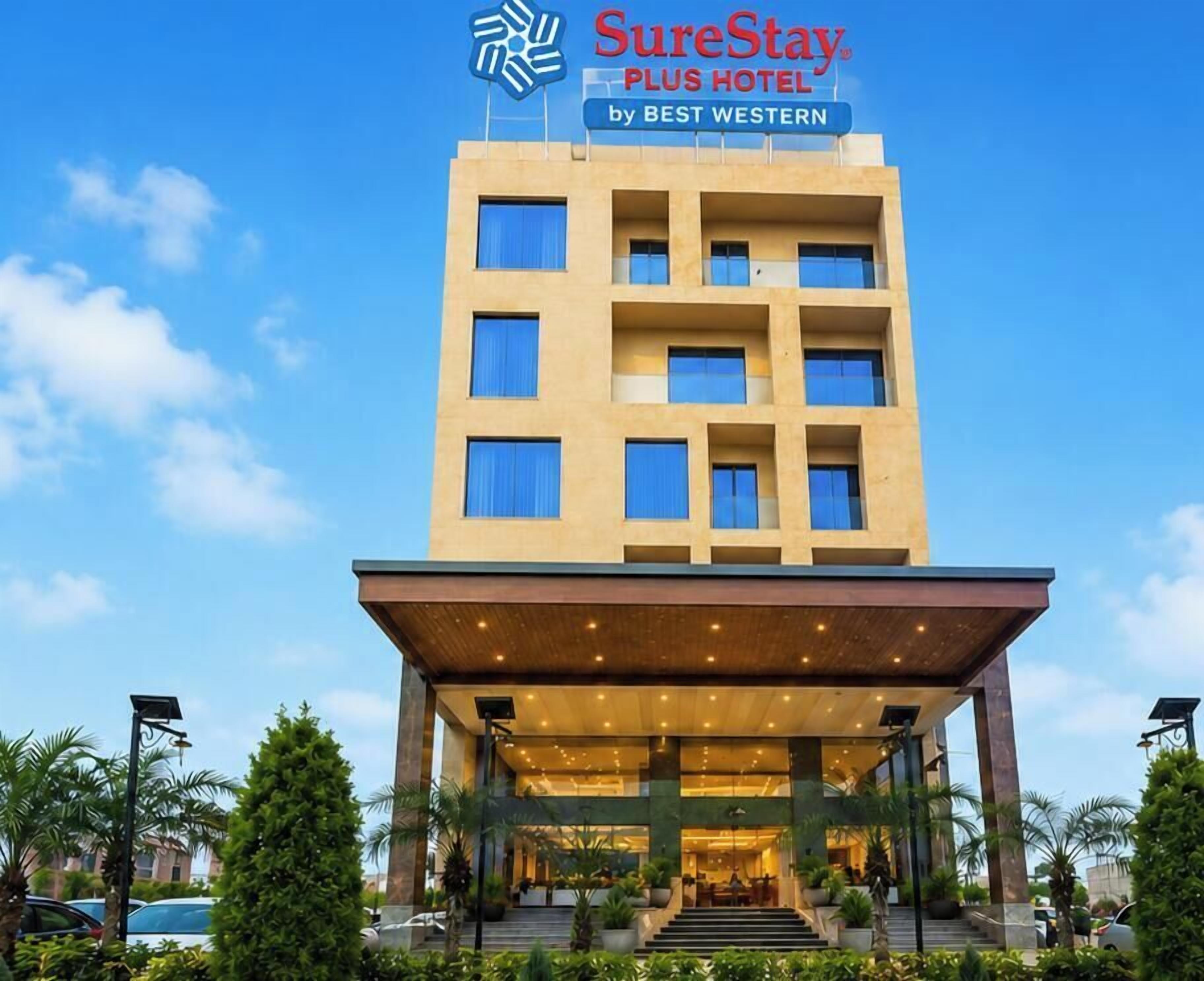 A hotel with a modern design, featuring a prominent entrance with a covered area and a sign indicating it's part of the SureStay Plus Hotel chain by Best Western.