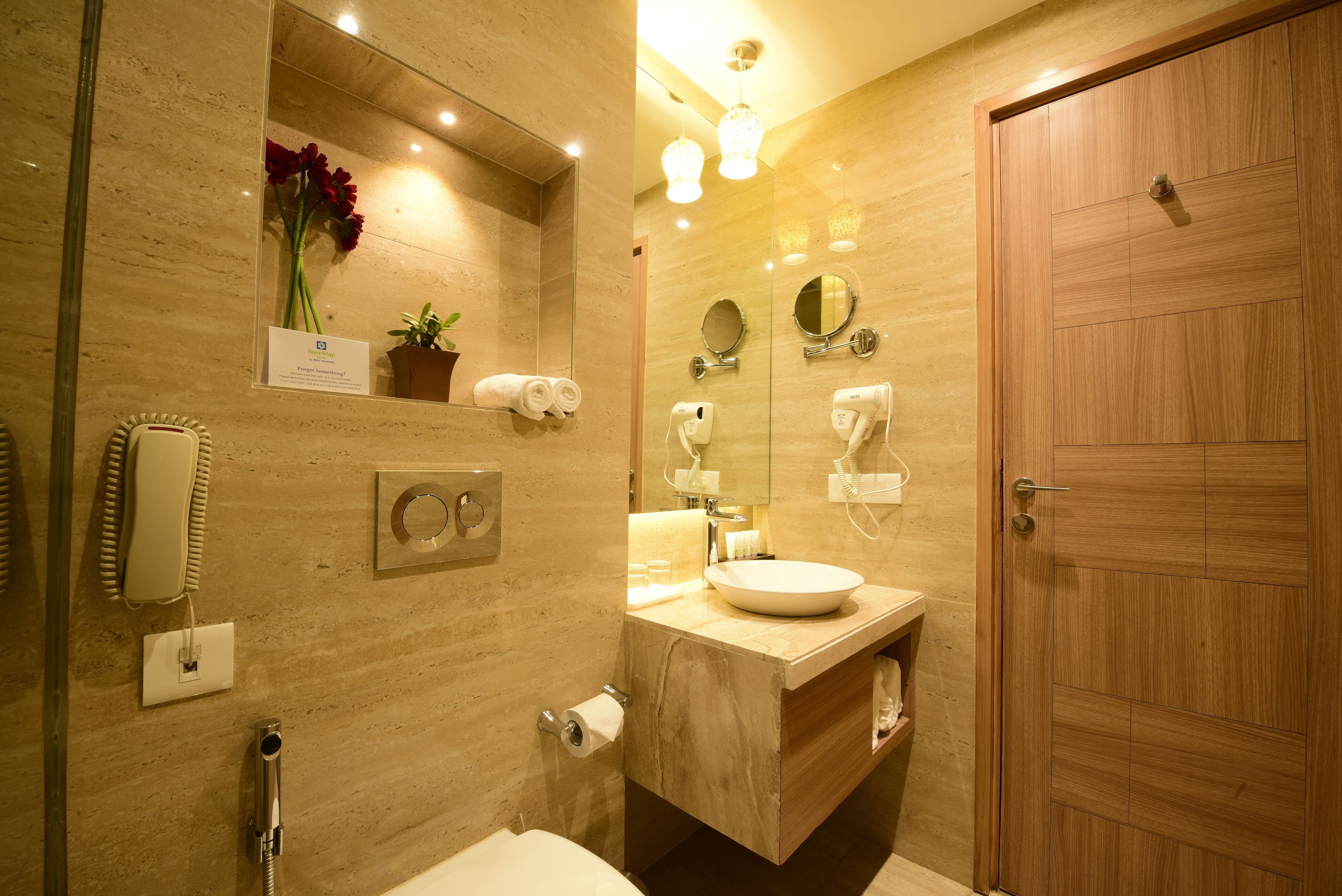 Un bagno moderno con una parete in marmo, una porta in legno, un lavandino con specchio, un appendi-asciugamani e un telefono.