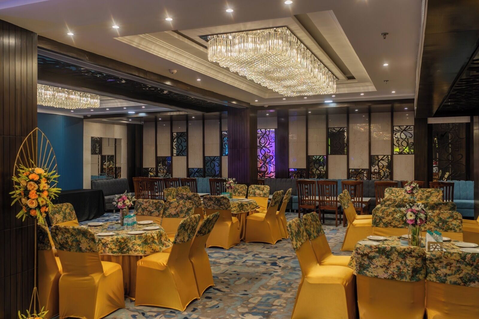 Un salón de banquetes con mesas redondas, sillas amarillas y una lámpara de araña grande.