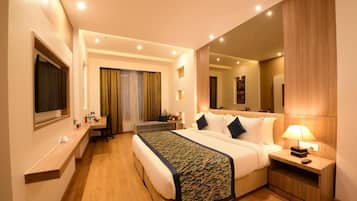 Habitación de hotel con una cama grande, mesitas de noche, un escritorio y un espejo.