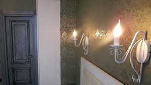 A bedroom with a bed, a wardrobe, and wall-mounted sconces. - Mini Hotel D'Rami (Almaty)