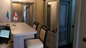 A dining area with a table and chairs, a laptop on the table, and a door with a mirror. - Mini Hotel D'Rami (Almaty)
