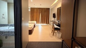 A modern hotel room with a bathroom, a desk, and a bed. - J & Y Lodge Hotel (Chonburi)