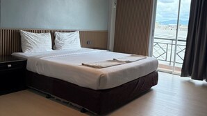 A hotel room with a bed, a nightstand, an air conditioning unit, and a view of the outside. - J & Y Lodge Hotel (Chonburi)